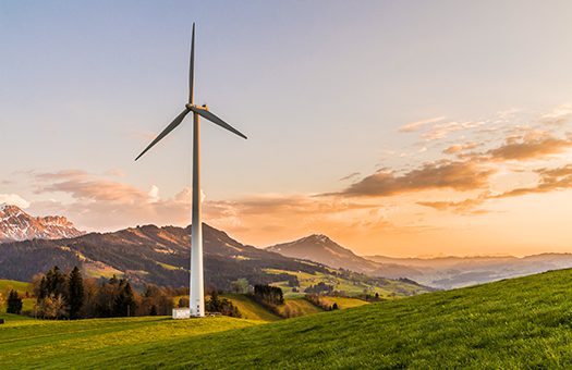 A wind turbine is installed in the green valley which produce the green energy.